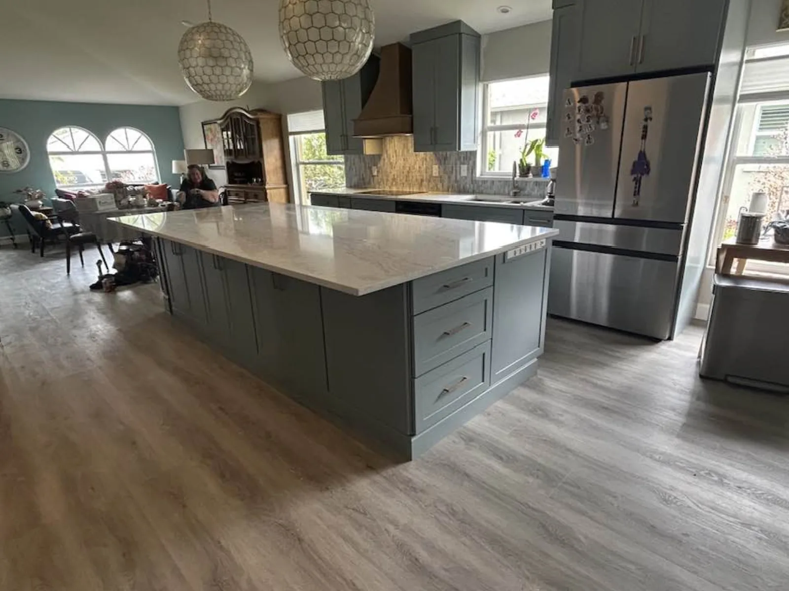 Gray cabinets with oversized quartz island opening to dining area