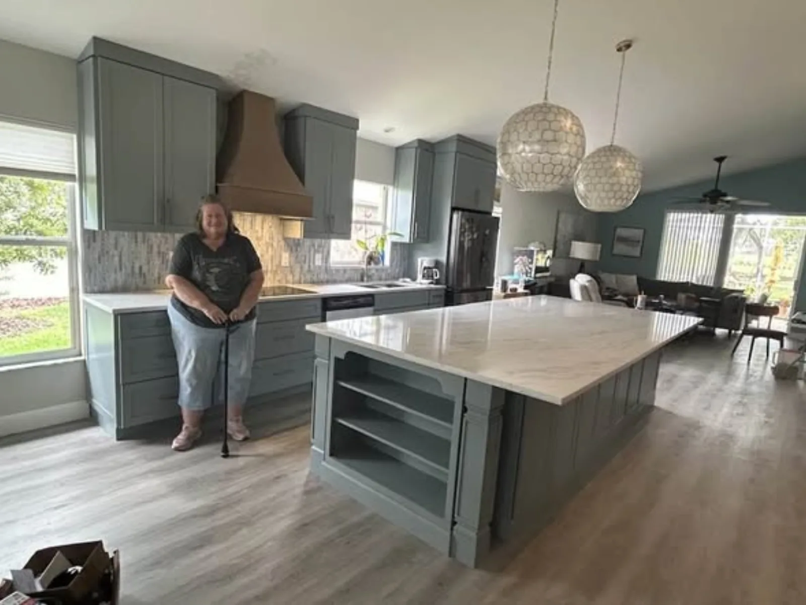 Finished gray kitchen with wood hood, large island, and chandeliers